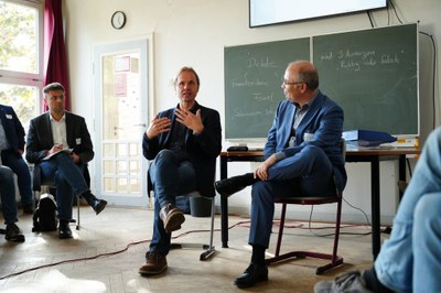 Marko Neumann Diskussion Marko Neumann sitzt in einem Stuhlkreis in einem Klassenzimmer und diskutiert mit einer weiteren Person